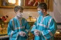 Two young sextons with protective masks in Orthodox church