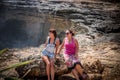 Two young and women on the rocks near the wild ocean. Storm, huge waves coming and splashing. Tropical island Nusa Royalty Free Stock Photo