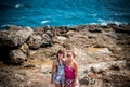 Two young and women on the rocks near the wild ocean. Storm, huge waves coming and splashing. Tropical island Nusa Royalty Free Stock Photo
