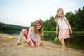 Two young sisters having fun on a sandy lake beach on warm and sunny summer day. Kids playing by the river Royalty Free Stock Photo