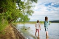 Two young sisters having fun on a sandy lake beach on warm and sunny summer day. Kids playing by the river Royalty Free Stock Photo