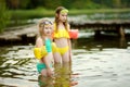 Two young sisters having fun on a sandy lake beach on warm and sunny summer day. Kids playing by the river Royalty Free Stock Photo