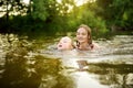 Two young sisters having fun on a sandy lake beach on warm and sunny summer day. Kids playing by the river Royalty Free Stock Photo