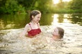 Two young sisters having fun on a sandy lake beach on warm and sunny summer day. Kids playing by the river Royalty Free Stock Photo