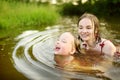 Two young sisters having fun on a sandy lake beach on warm and sunny summer day. Kids playing by the river Royalty Free Stock Photo