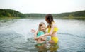 Two young sisters having fun on a sandy lake beach on warm and sunny summer day. Kids playing by the river Royalty Free Stock Photo