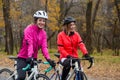 Two Young Smiling Female Cyclists with Road Bicycles Resting and in Park in Cold Autumn Day. Healthy Lifestyle. Royalty Free Stock Photo