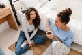 Two girls talking and drinking coffee while sitting over bed at home Royalty Free Stock Photo