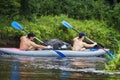 Two young sports guy in a boat rowing oars on the water. Kayaking along the river in the summer season