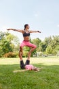 Two young sportswomen doing acrobatic yoga or yoga partner together outdoors in fitness park. Athletic, healthy and