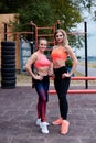 Two young strong women, wearing colorful sports outfit,doing fitness exercises outside in summer.Workout power female training to