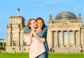 Student girls having fun and dancing and piggybacking on the grass near famous landmark in Berlin - Bundestag building.