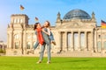 Young student girls having fun and dancing and piggybacking on the grass near famous landmark in Berlin - Bundestag building.