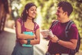 Two young students standing on street with books and talking Funny conversation Royalty Free Stock Photo