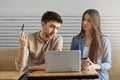 Two young students in stylish clothes sitting in cafeteria talking about study project and looking at laptop monitor Royalty Free Stock Photo