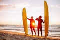 Two young surfers in black wetsuit with yellow surfing longboards on a ocean coast at sunset ocean. Water sport Royalty Free Stock Photo