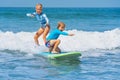 Two young surfers ride with fun on one surfboard Royalty Free Stock Photo