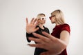 Two young teenage girls in fashion youth glasses in stylish dresses cover camera with their palm and look at each other near Royalty Free Stock Photo