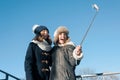 Two young teenage girls having fun outdoors, happy smiling girlfriends in winter clothes taking selfie, positive people and Royalty Free Stock Photo