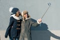 Two young teenage girls having fun outdoors, happy smiling girlfriends in winter clothes taking selfie, positive people and Royalty Free Stock Photo