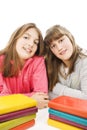 Two young teenage girls with pile colored book.