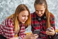 Two young teenage girls using mobile phones while sitting on a couch at home Royalty Free Stock Photo