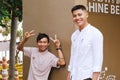 Two young Thai guys in hotel uniforms are smiling and looking at the camera