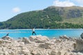 Two young tourists enjoy experience of rocky foreshore taking photo