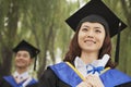 Two Young University Graduates Holding Diplomas, Woman in Front