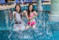 Two young woman friends splashing water in swimming pool Royalty Free Stock Photo