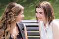 Two young woman sisters sitting on a bench in a park