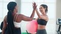 Two young woman in sportswear workout routines using exercise ball in fitness gym with trainer. Royalty Free Stock Photo