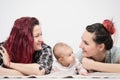 Two young women with a baby on a white background. Same-sex marriage and adoption, homosexual lesbian couple.