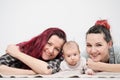 Two young women with a baby on a white background. Same-sex marriage and adoption, homosexual lesbian couple.