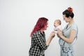 Two young women with a baby on a white background. Same-sex marriage and adoption, homosexual lesbian couple.