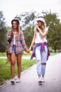Two young women holding hands walking in green park. Best friends Royalty Free Stock Photo