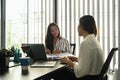 Two women colleagues sitting at office desk and talking about project startup ideas. Royalty Free Stock Photo