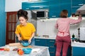 Two young women cook in the kitchen using online recipes in a smartphone. Concept of cooking at home, LGBT couples