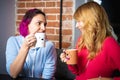 Two young women with the cups of tea and coffee talking