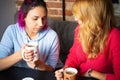 Two young women with the cups of tea and coffee talking