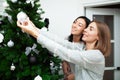 Two young women decorate the Christmas tree, preparing for the New Year`s celebration Royalty Free Stock Photo