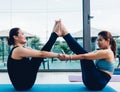 Two young woman doing pose yoga pull arm together