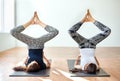 Two young women doing yoga asana bound angle shoulderstand pose