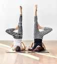 Two young women doing yoga asana supported shoulderstand