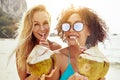 Two young women drinking from coconuts on a tropical beach Royalty Free Stock Photo