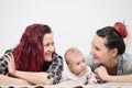 Two young women with a baby on a white background. Same-sex marriage and adoption, homosexual lesbian couple.