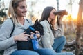 Two young women enjoying in forest hiking with their dog