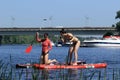 Two young women float on swimming boards and pluck water lilies from a wide river. Royalty Free Stock Photo