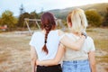 Two young women friends on her back with hair in a braid and blonde hair hugging each other in the countryside. Friendship concept