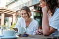 Two young women friends are sitting in a cafe drinking coffee and discussing the news, joyful and happy coffee break Royalty Free Stock Photo